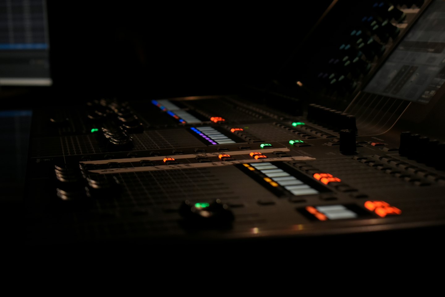 Professional audio mixing console with many lit buttons and faders.