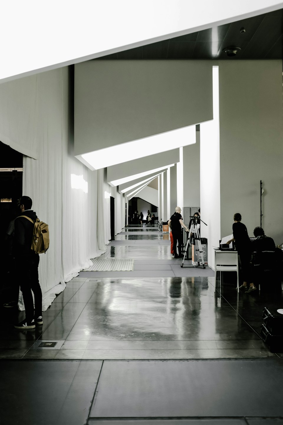 Technicians set up professional audio and video gear in a modern hallway.