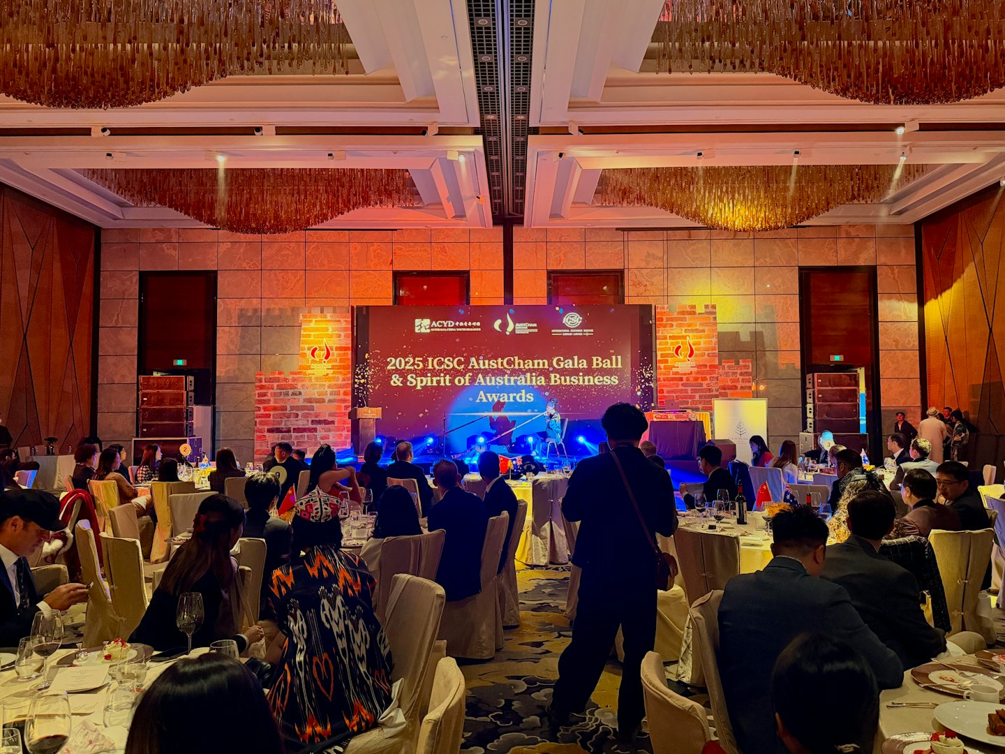 Business professionals seated at round tables during a corporate gala.