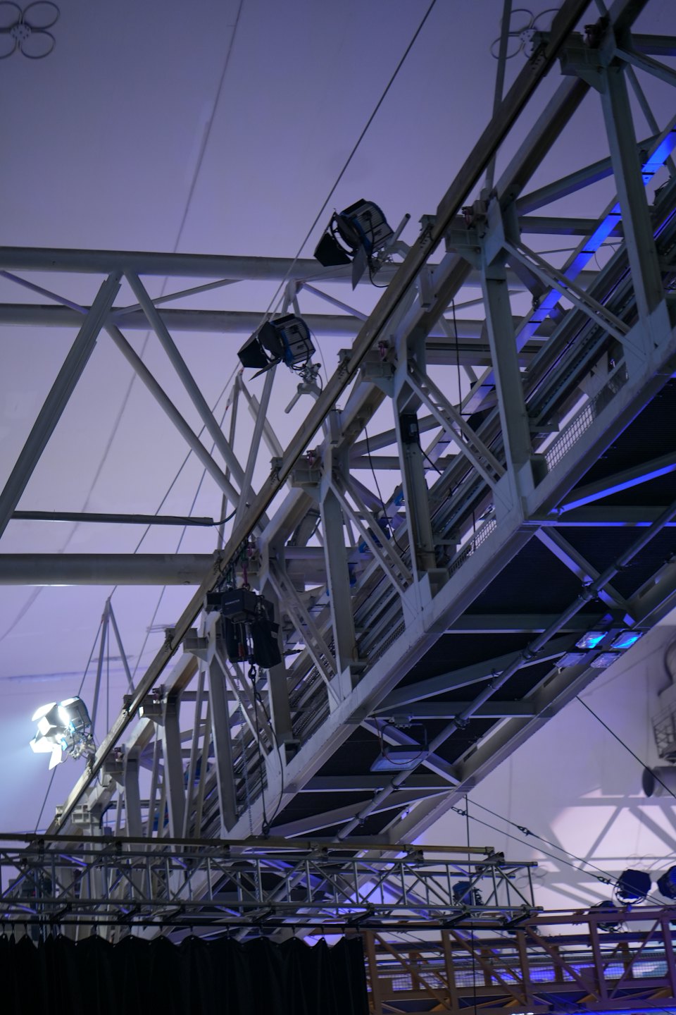 Intricate metal truss structure with stage lights on a venue ceiling.