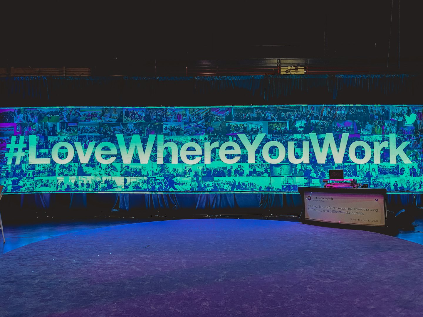 Large stage with a screen displaying a social media hashtag.