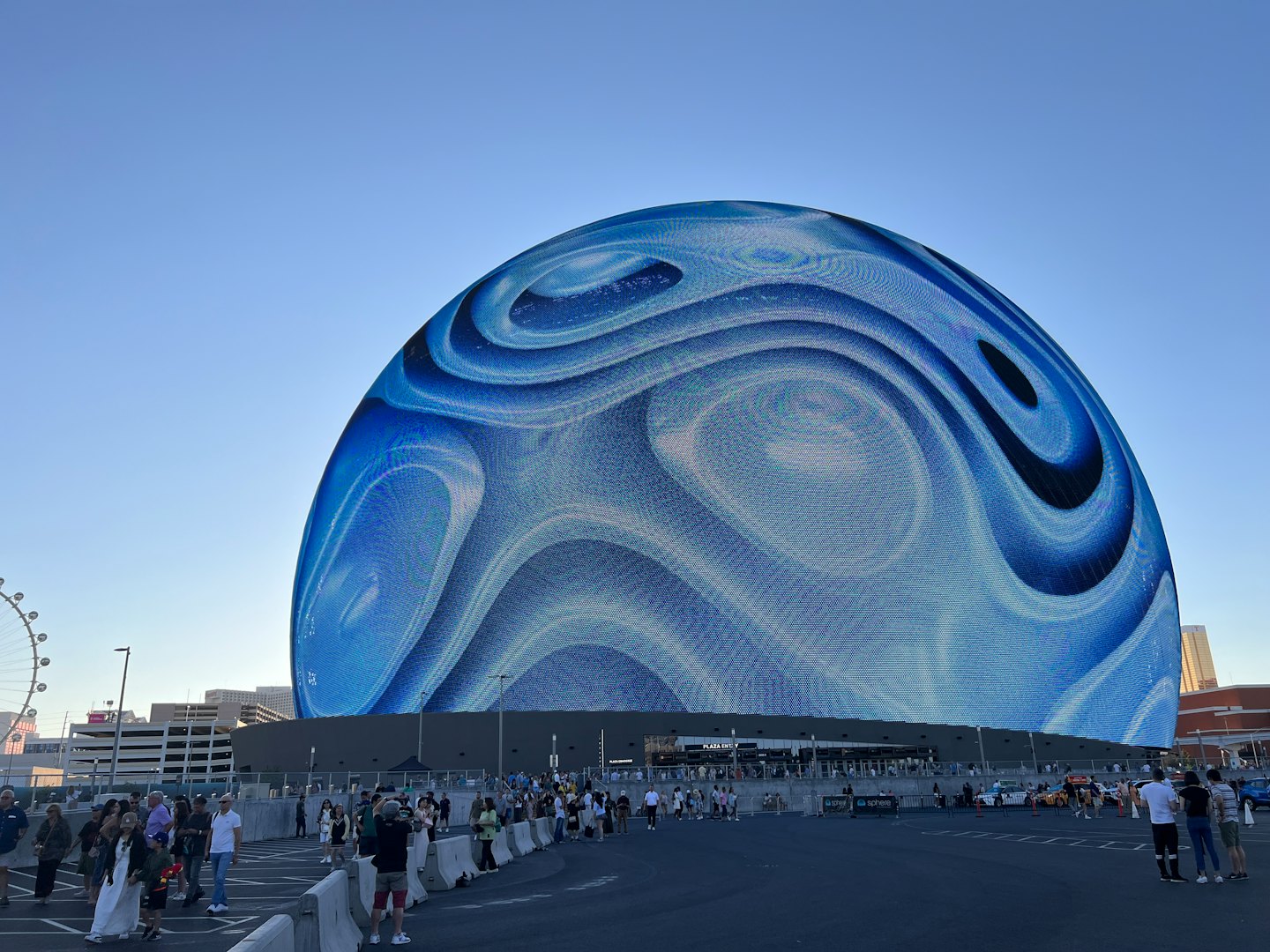 Crowd gathers at the base of a glowing blue spherical building.
